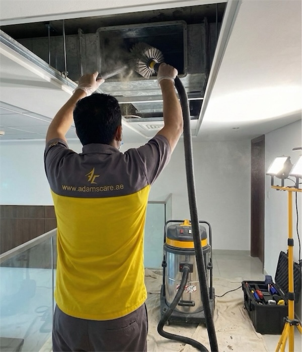 Professional cleaning a ceiling duct with a rotating brush and vacuum machine for expert HVAC work in Dubai.