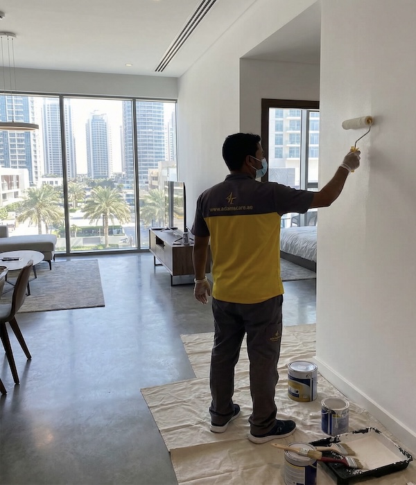 Our home painting services captured in action as a professional applies crisp white paint with a roller.