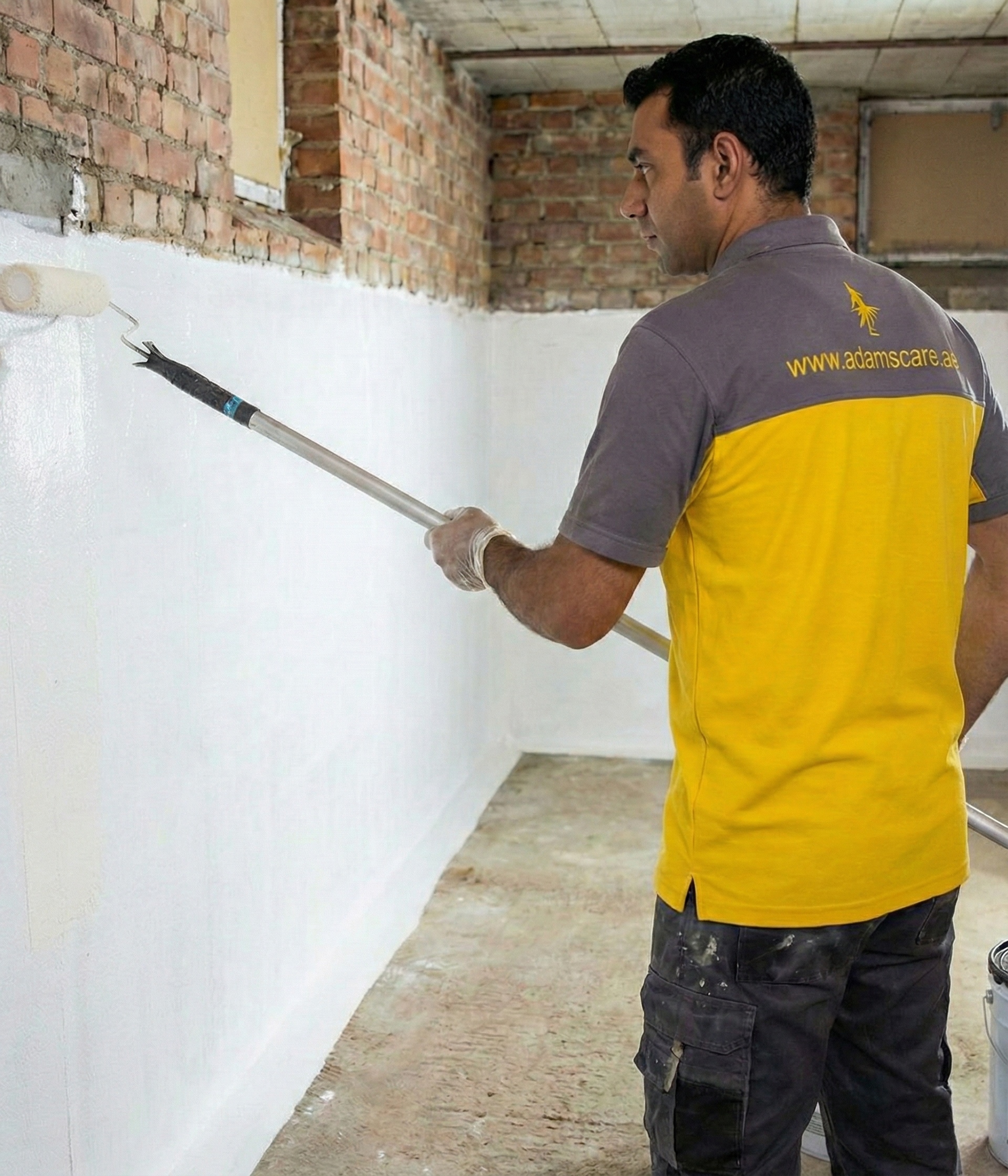 Expert technician coating interior brick and concrete walls with white protective waterproofing sealant.