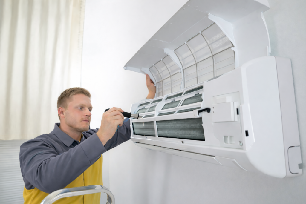 Technician removing air conditioner filter for routine care.
