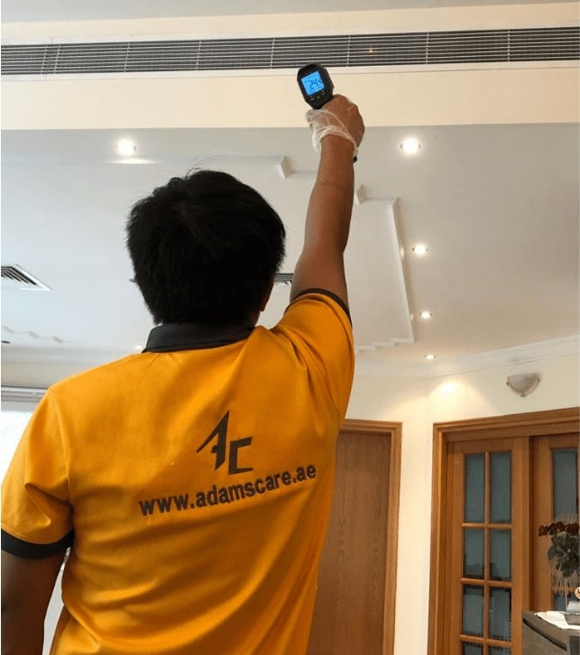 Adams Care’s AC technician testing air conditioning temperature after repairs.