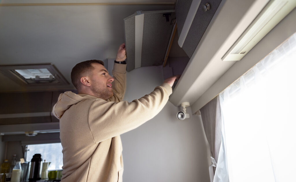 Person doing routine maintenance on a wall-mounted air conditioner, replacing the filters and coils for maximum efficiency.